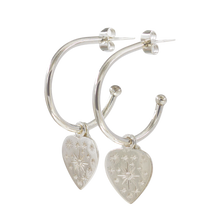 A pair of silver hoop earrings with heart charms and small star-shaped embellishments.