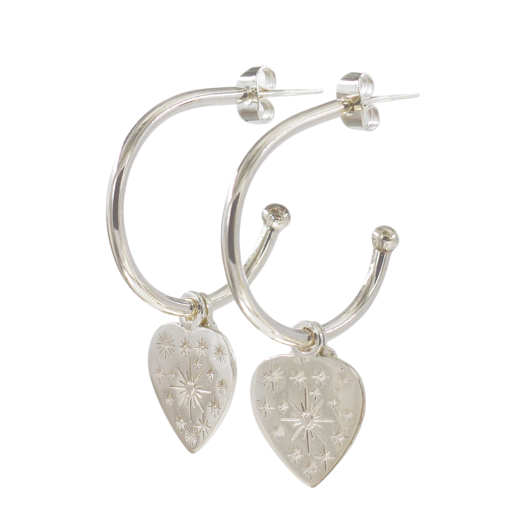A pair of silver hoop earrings with heart charms and small star-shaped embellishments.