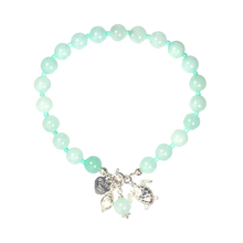 Turquoise beaded bracelet with silver charms on a white background