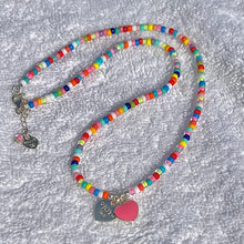 Colorful beaded lanyard with heart and round charm on a textured white background