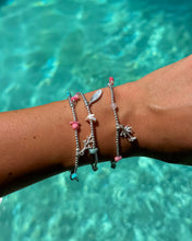 Stacked silver bead bracelets with ocean-inspired charms and gemstones